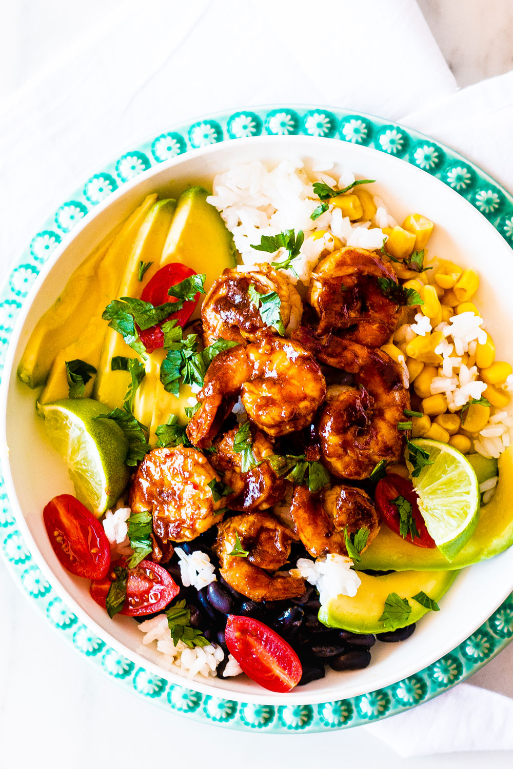These Adobo Shrimp Bowls are loaded with flavorful and juicy shrimp, rice, black beans, tomatoes, avocados, and corn, then drizzled with a fresh cilantro lime dressing! https://www.spotebi.com/recipes/adobo-shrimp-bowls-cilantro-lime-dressing/