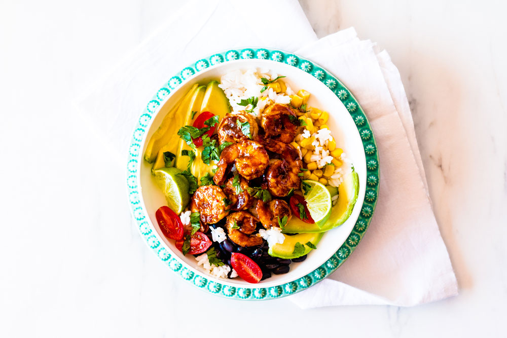 These Adobo Shrimp Bowls are loaded with flavorful and juicy shrimp, rice, black beans, tomatoes, avocados, and corn, then drizzled with a fresh cilantro lime dressing! https://www.spotebi.com/recipes/adobo-shrimp-bowls-cilantro-lime-dressing/